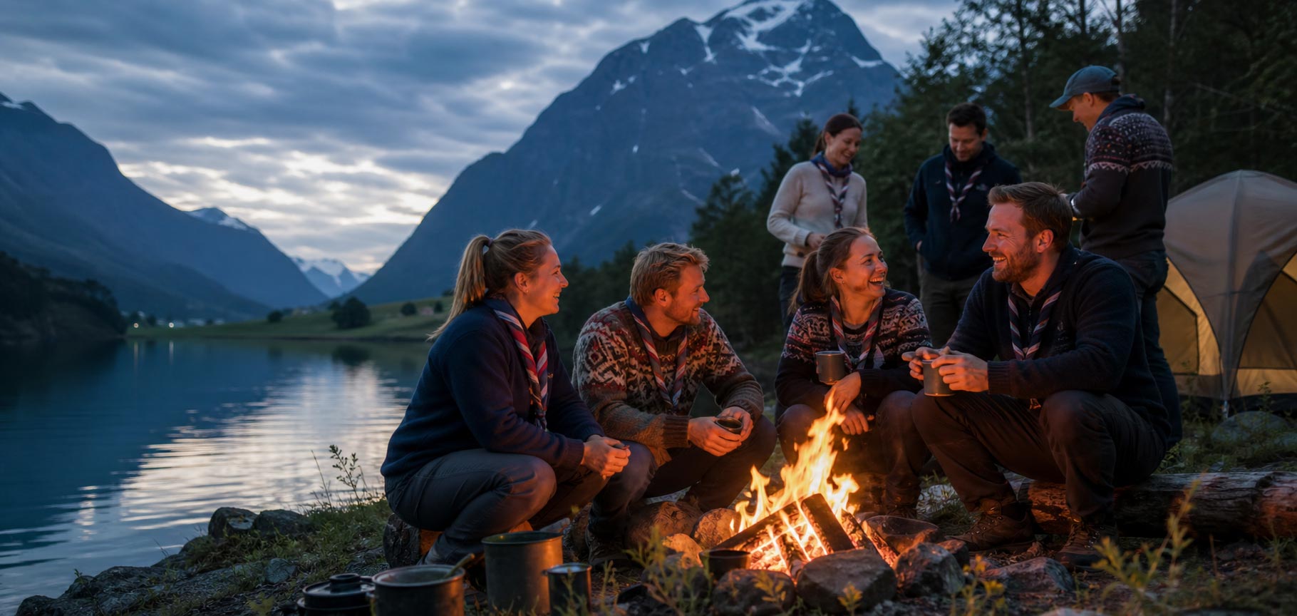 Speidere rundt bålet ved fjorden i blåtimen
